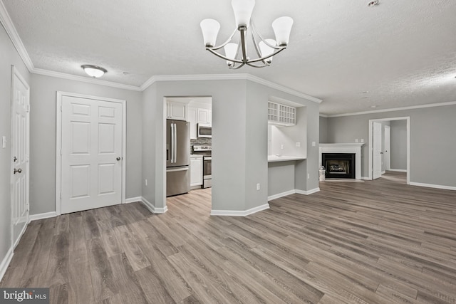 unfurnished living room featuring a chandelier, a textured ceiling, light hardwood / wood-style floors, and ornamental molding