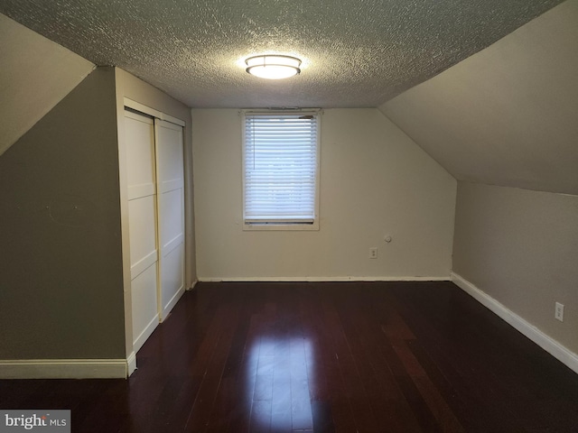 additional living space with a textured ceiling, dark hardwood / wood-style floors, and vaulted ceiling