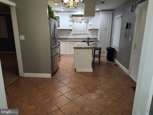 kitchen with dark tile patterned flooring, a center island, white cabinetry, and backsplash