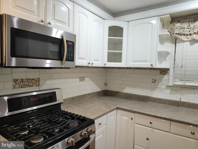 kitchen with tasteful backsplash, white cabinets, and appliances with stainless steel finishes