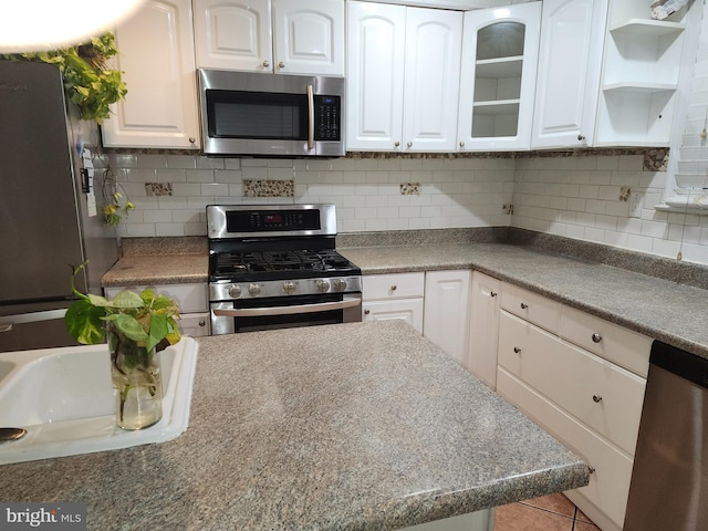 kitchen featuring decorative backsplash, white cabinetry, light tile patterned floors, and stainless steel appliances