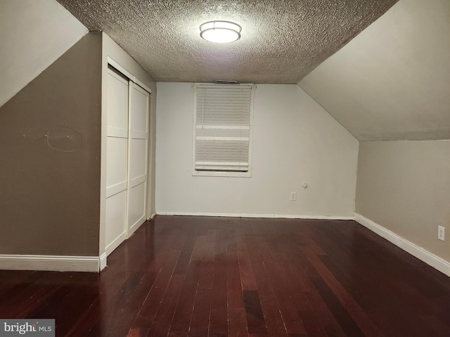 additional living space with vaulted ceiling, dark hardwood / wood-style flooring, and a textured ceiling