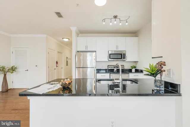 kitchen featuring white cabinets, crown molding, light wood-type flooring, kitchen peninsula, and stainless steel appliances