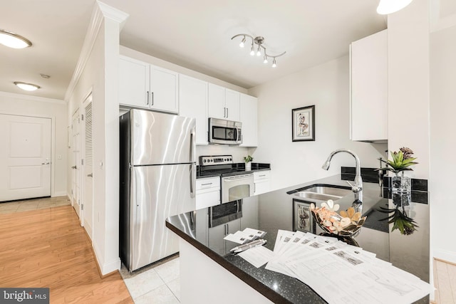 kitchen featuring kitchen peninsula, stainless steel appliances, sink, light hardwood / wood-style floors, and white cabinetry