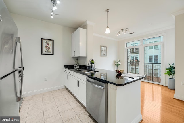 kitchen with white cabinets, sink, hanging light fixtures, kitchen peninsula, and stainless steel appliances