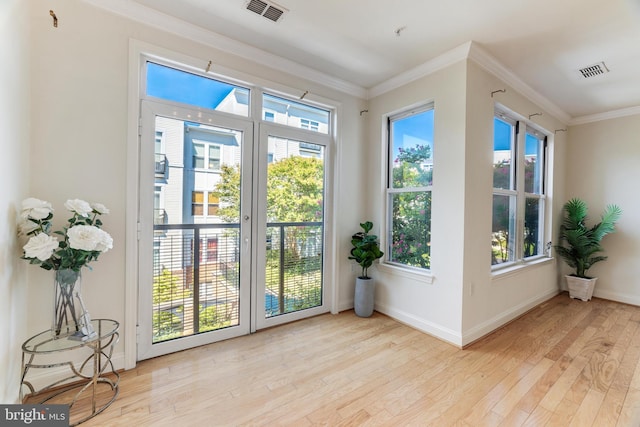 doorway to outside with light wood-type flooring, crown molding, and a wealth of natural light