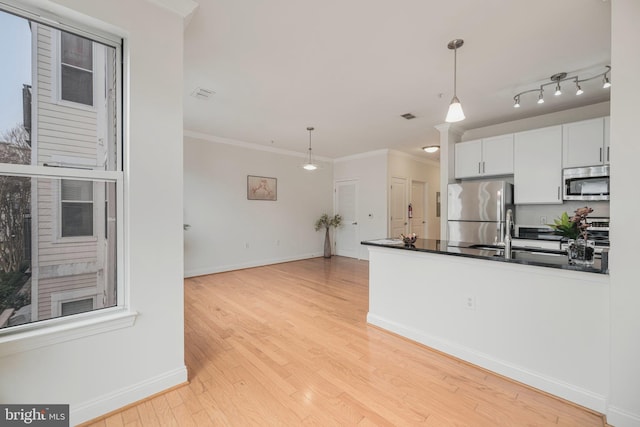 kitchen with stainless steel appliances, white cabinetry, hanging light fixtures, and ornamental molding