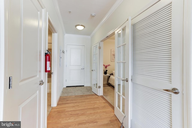 corridor with crown molding, french doors, and light hardwood / wood-style floors