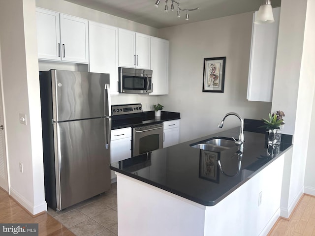 kitchen with kitchen peninsula, sink, white cabinets, and stainless steel appliances