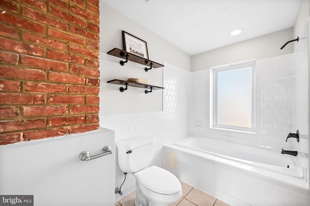 bathroom featuring tile walls, tiled shower / bath, toilet, and tile patterned floors