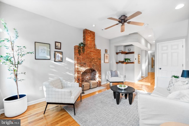 living area featuring baseboards, ceiling fan, wood finished floors, a fireplace, and recessed lighting