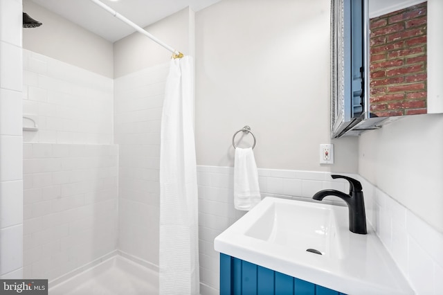 full bath featuring tiled shower and a sink