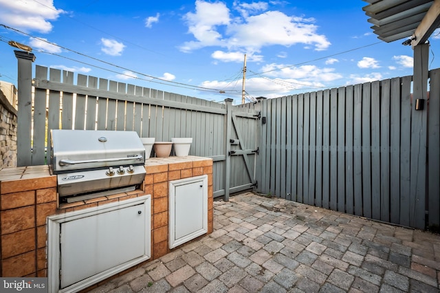 view of patio with exterior kitchen, a gate, fence, and area for grilling