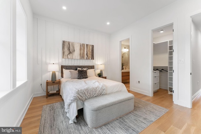 bedroom featuring connected bathroom, light hardwood / wood-style flooring, a spacious closet, and a closet