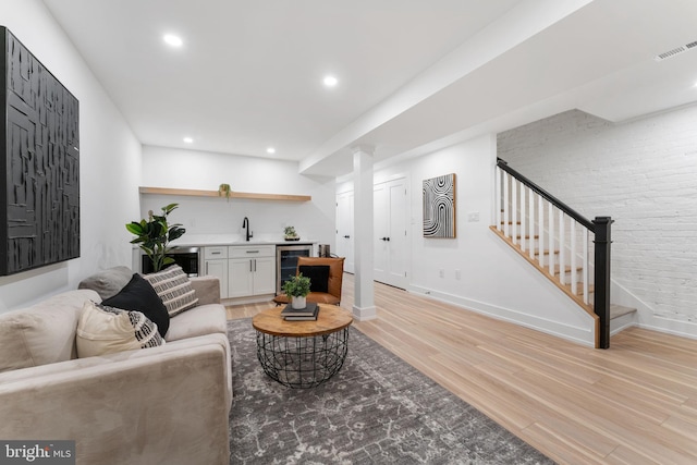 living room with indoor wet bar, wine cooler, and light hardwood / wood-style flooring