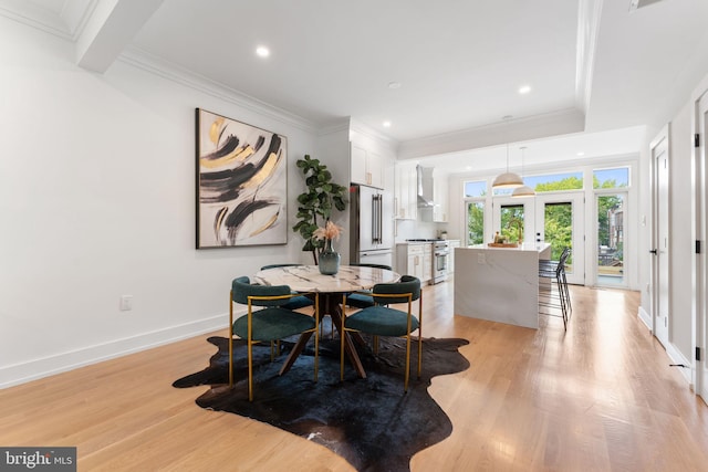 dining area featuring light hardwood / wood-style floors, crown molding, and french doors