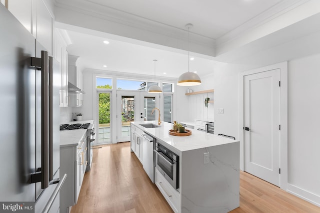 kitchen featuring a kitchen island with sink, white cabinets, decorative light fixtures, light stone counters, and stainless steel appliances