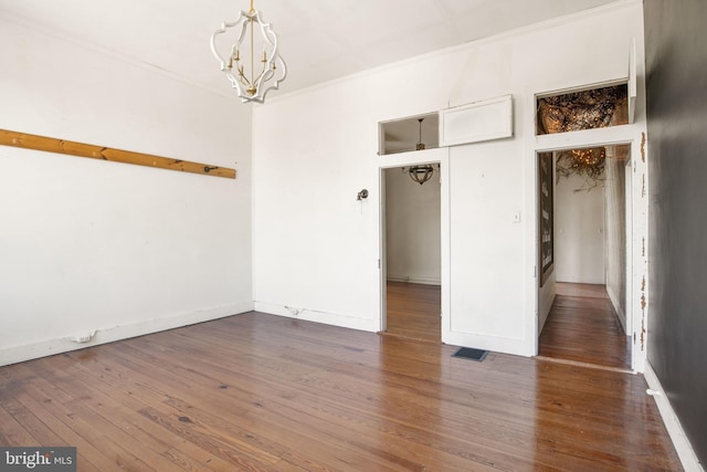 unfurnished bedroom featuring a chandelier, crown molding, dark wood-type flooring, and a closet