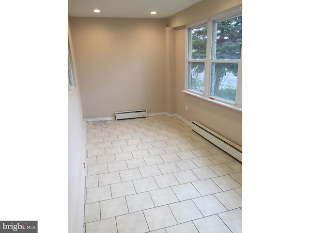 tiled spare room featuring a wealth of natural light and a baseboard heating unit