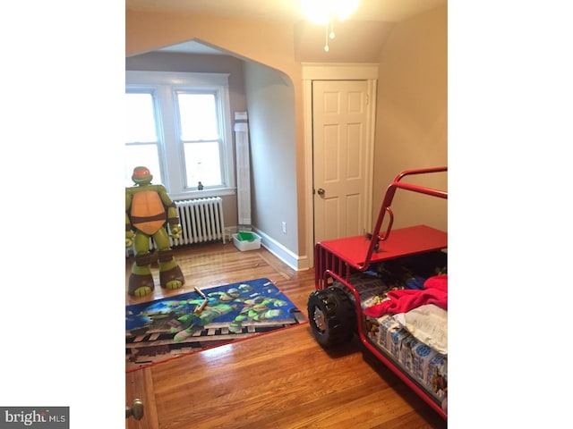 playroom with lofted ceiling, wood-type flooring, and radiator heating unit