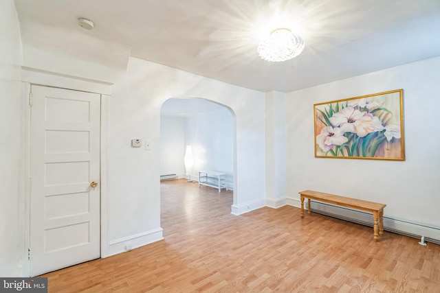 unfurnished room featuring baseboard heating and light wood-type flooring