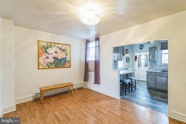 interior space with a baseboard radiator, an inviting chandelier, and light hardwood / wood-style floors