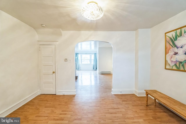 corridor featuring a notable chandelier, light wood-type flooring, and baseboard heating