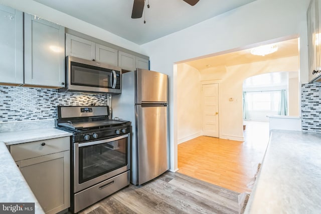 kitchen featuring decorative backsplash, gray cabinets, light wood-type flooring, and stainless steel appliances