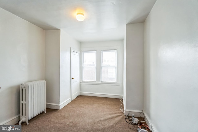 carpeted spare room featuring radiator heating unit