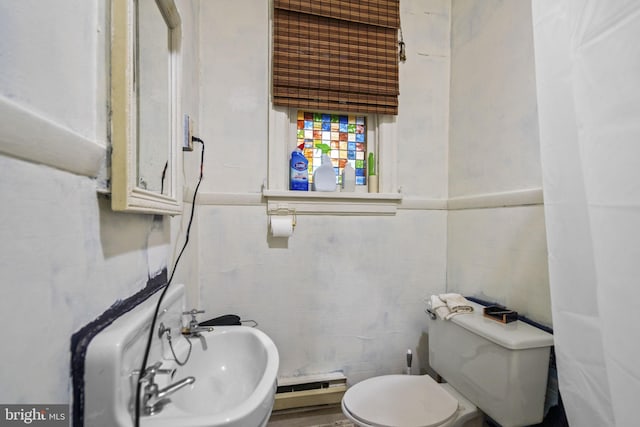 bathroom featuring toilet, tile walls, a baseboard heating unit, and sink