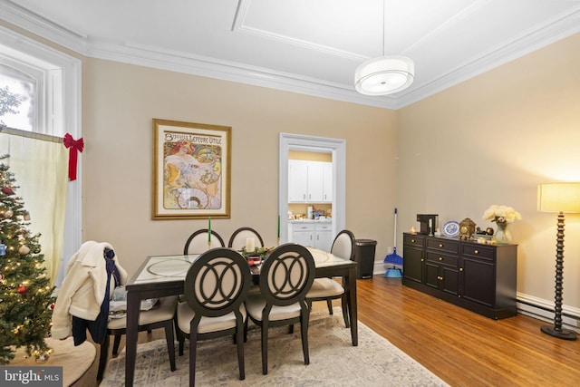 dining room with ornamental molding, baseboard heating, and light hardwood / wood-style flooring