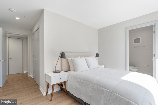 bedroom featuring connected bathroom and light hardwood / wood-style flooring