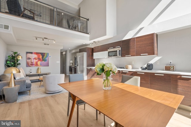 dining area featuring light hardwood / wood-style flooring and a high ceiling