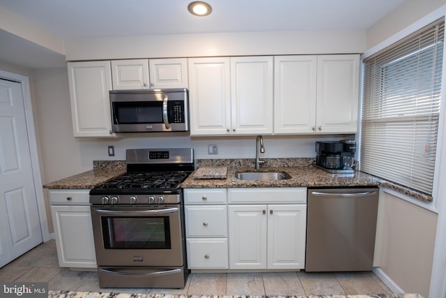 kitchen with white cabinets, sink, appliances with stainless steel finishes, and dark stone counters