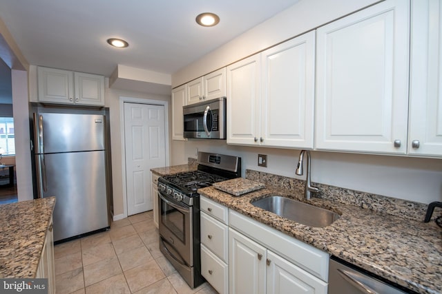 kitchen featuring sink, light tile patterned floors, light stone counters, white cabinets, and appliances with stainless steel finishes