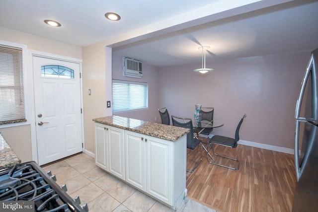 kitchen featuring stainless steel refrigerator, white cabinetry, hanging light fixtures, light stone counters, and light tile patterned floors