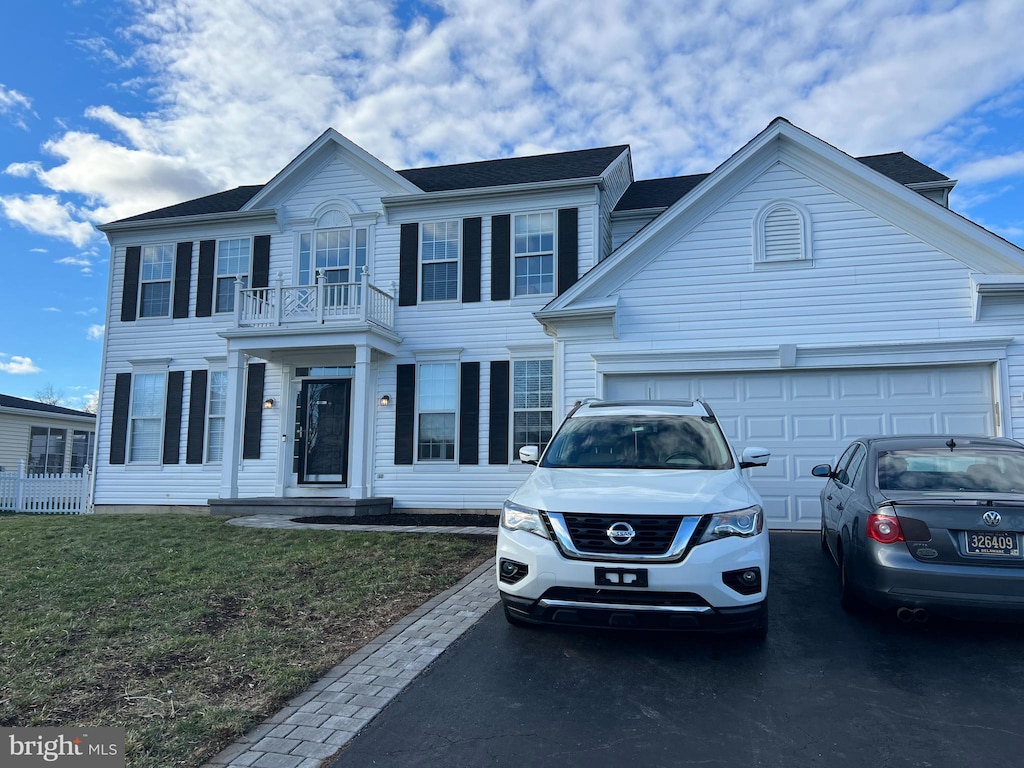 view of front of home featuring a balcony, a front lawn, and a garage