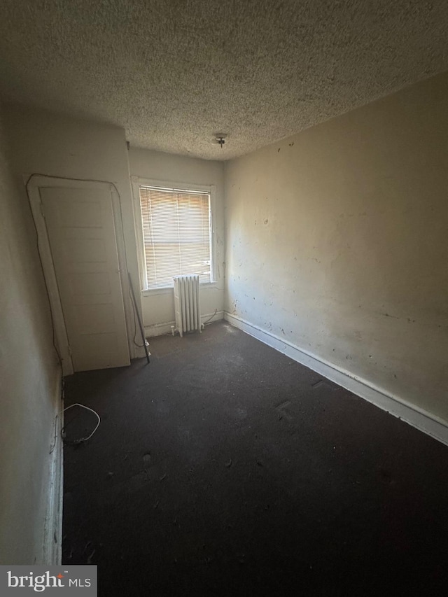 spare room featuring radiator heating unit and a textured ceiling