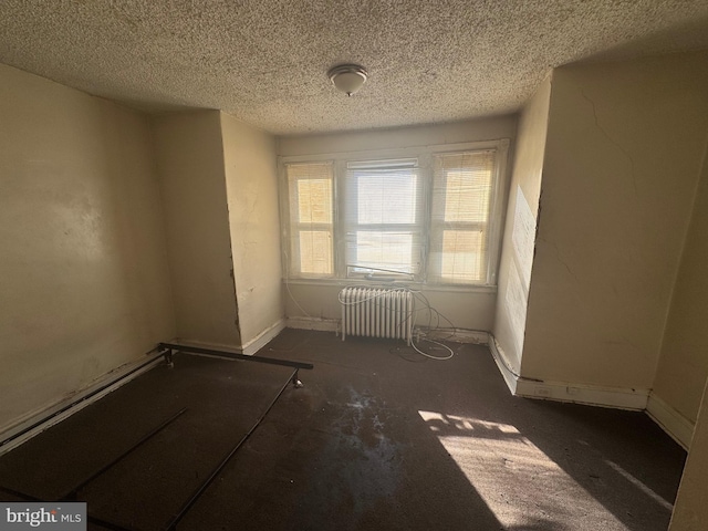 empty room with a textured ceiling and radiator