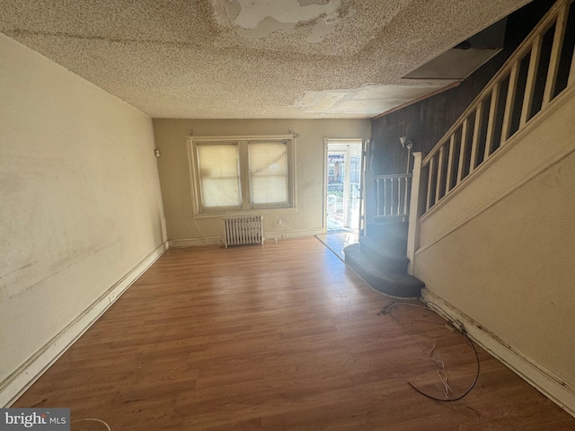 unfurnished living room featuring wood-type flooring, a textured ceiling, and radiator