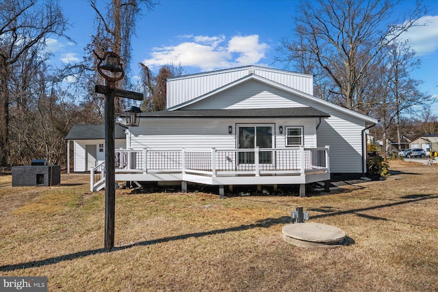 rear view of property featuring a wooden deck and a lawn