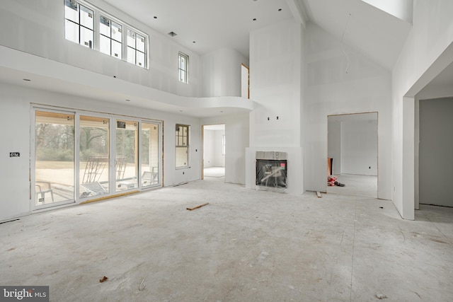 unfurnished living room with a high end fireplace and a towering ceiling