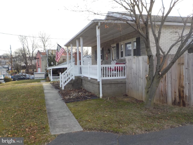 view of side of property featuring a lawn and covered porch