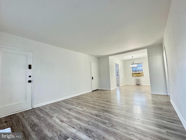 unfurnished living room with radiator, light hardwood / wood-style flooring, and a chandelier