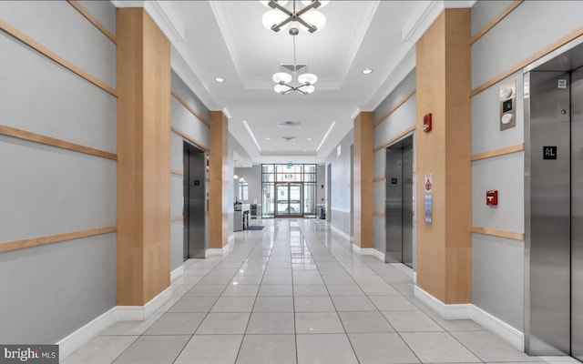 hallway featuring a raised ceiling, crown molding, elevator, light tile patterned flooring, and a chandelier