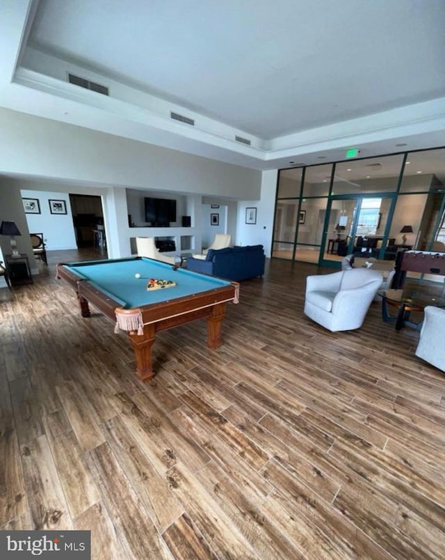 recreation room with a tray ceiling, hardwood / wood-style floors, and billiards