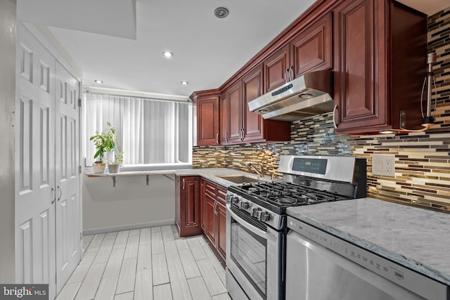 kitchen featuring light stone countertops, appliances with stainless steel finishes, sink, and decorative backsplash