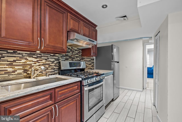 kitchen featuring sink, light hardwood / wood-style flooring, stainless steel appliances, light stone countertops, and backsplash