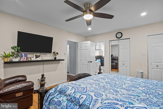 bedroom featuring hardwood / wood-style flooring, multiple closets, and ceiling fan