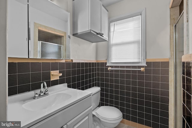 bathroom featuring an enclosed shower, vanity, toilet, and tile walls